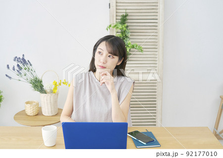 リビングでノートパソコンの前で考える女性 リビングでノートパソコンの前で考える女性 92177010