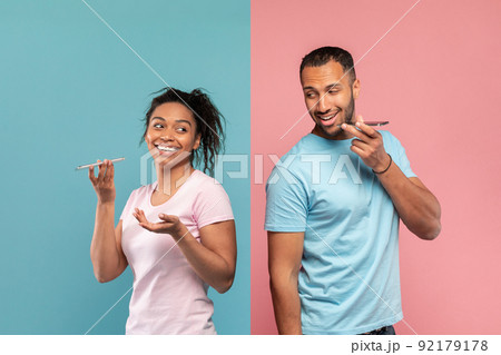 Technology and communication concept. Black woman and man recording audio messages on their cellphones 92179178