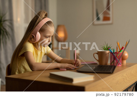 Schoolgirl Using Laptop And Taking Notes Doing Homework At Home Schoolgirl Using Laptop And Taking Notes Doing Homework At Home 92179780