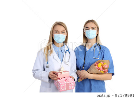 Female doctor and nurse with gifts isolated on white background Female doctor and nurse with gifts isolated on white background 92179991
