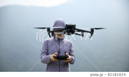 Woman remotel control a flying drone in spring forest Woman remotel control a flying drone in spring forest 92181024