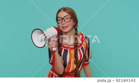 Smiling ginger girl talking with megaphone, proclaiming news, loudly announcing sale advertisement Smiling ginger girl talking with megaphone, proclaiming news, loudly announcing sale advertisement 92184143