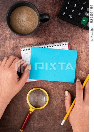 Hands Of Woman Having Pastel Color Paper With Copy Space, Coffee Cup And Stationery Over Wooden Background. Businesswoman Displaying Business Branding And Promotion Ideas. 92184494