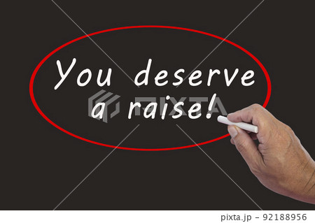 Male hand writes in white chalk pencil the word YOU DESERVE A RAISE. Male hand writes in white chalk pencil the word YOU DESERVE A RAISE. 92188956