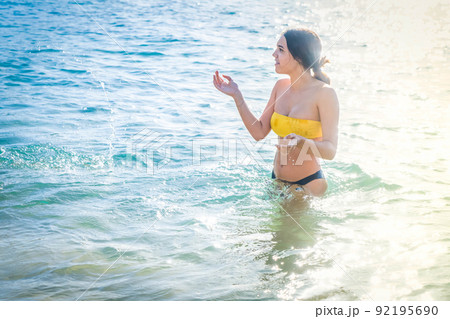 Young happy woman in bikini swimsuit swimming in sea 92195690