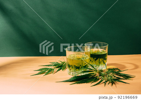 Green drink from SBD hemp creative green background with hard shadows, cannabis cocktail Green drink from SBD hemp creative green background with hard shadows, cannabis cocktail 92196669