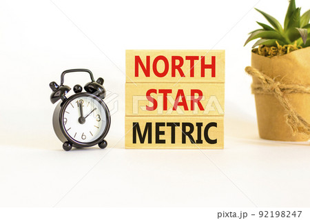 North star metric symbol. Concept words North star metric on wooden blocks on a beautiful white table white background. Black alarm clock. Business, finacial and north star metric concept. Copy space. 92198247