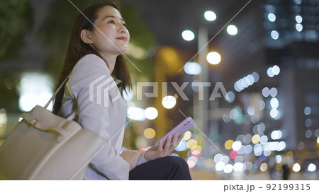 仕事終わりにスマホを見るビジネスウーマン 女性 スマートフォン 92199315