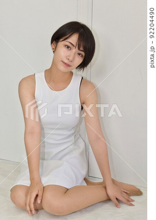 室内で座りくつろぐワンピースを着た微笑む若い女性のポートレート 室内で座りくつろぐワンピースを着た微笑む若い女性のポートレート 92204490