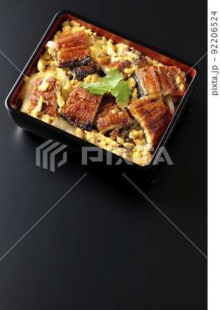 鰻の蒲焼きを卵でとじて三つ葉を乗せた鰻玉重を黒背景で俯瞰撮影 92206524