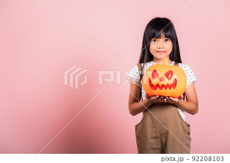 Asian little kid 10 years old holding carved Halloween pumpkin Asian little kid 10 years old holding carved Halloween pumpkin 92208103