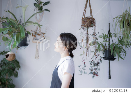 明るい植物のある室内でどこかを見つめるワンピース姿の日本人女性 92208113