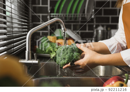 Asian hands woman washing vegetables broccoli and preparation healthy food in kitchen. Asian hands woman washing vegetables broccoli and preparation healthy food in kitchen. 92211216