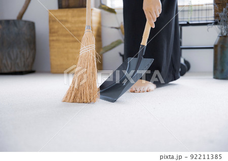 明るい植物の部屋でほうきで掃除する日本人女性 92211385