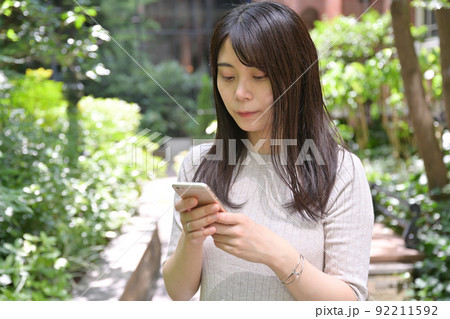 屋外でスマホの操作をする若い女性 屋外でスマホの操作をする若い女性 92211592