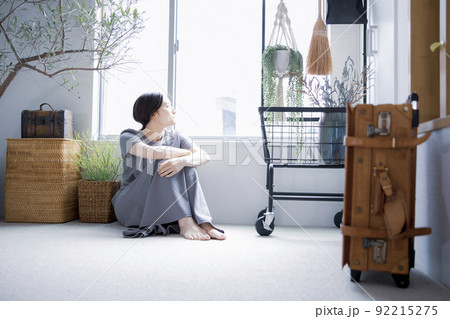 明るい植物のある窓辺の部屋で座って空を見上げて休憩する日本人女性 92215275