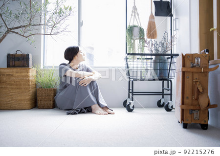 明るい植物のある窓辺の部屋で座って空を見上げて休憩する日本人女性 92215276