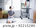 明るい植物のある窓辺の部屋で座って空を見上げて休憩する日本人女性 92215280
