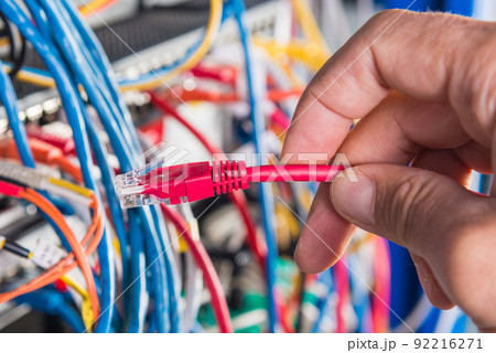 closeup of hand of administrator connecting network cable into switch 92216271