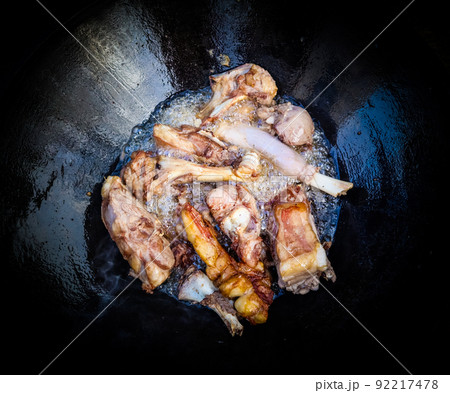 Lamb in a large cast-iron cauldron on fire. Pilaf cooking process. Lamb in a large cast-iron cauldron on fire. Pilaf cooking process. 92217478
