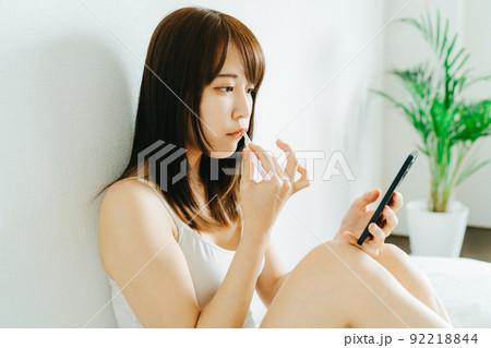 歯磨きしながらスマホをみる若い女性 歯磨きしながらスマホをみる若い女性 92218844