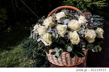 Bouquet of beautiful white roses in a wicker basket on a green background. Perfect for greeting card 92219555