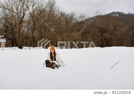 woman in the snow playing with a dog fun friendship winter holidays 92220028