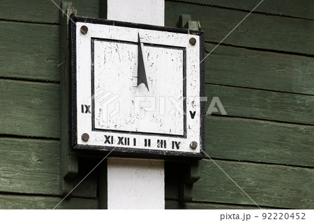 Vintage sundial placed on a green wooden wall Vintage sundial placed on a green wooden wall 92220452