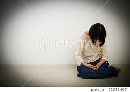 室内の床に座って悲しむミドル女性 92221407
