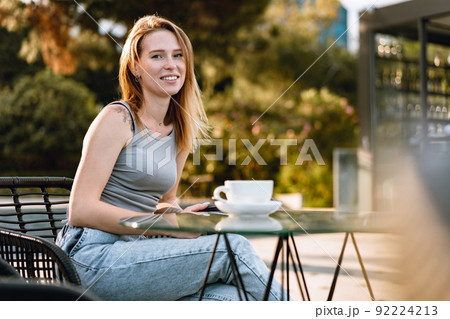 Beautiful cute young woman while drinking tea in modern street cafe Beautiful cute young woman while drinking tea in modern street cafe 92224213