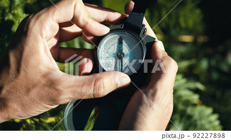 Hands of a boy opens the compass in the mountains to orient himself in the hike. Hands of a boy opens the compass in the mountains to orient himself in the hike. 92227898