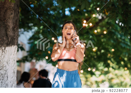 Attractive woman talking on mobile phone on a summer street. Attractive woman talking on mobile phone on a summer street. 92228077