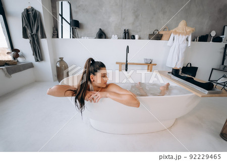 Relaxed lady taking bath, enjoying and relaxing while lying in bathtub Relaxed lady taking bath, enjoying and relaxing while lying in bathtub 92229465