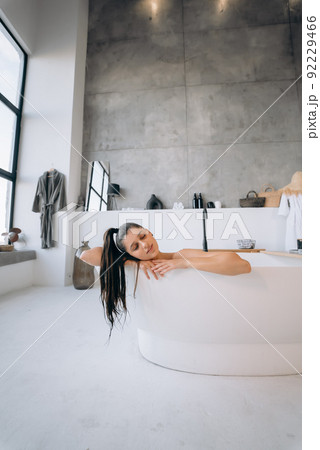 Relaxed lady taking bath, enjoying and relaxing while lying in bathtub Relaxed lady taking bath, enjoying and relaxing while lying in bathtub 92229466