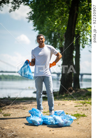 Guy with trash bag standing looking at camera Guy with trash bag standing looking at camera 92230907