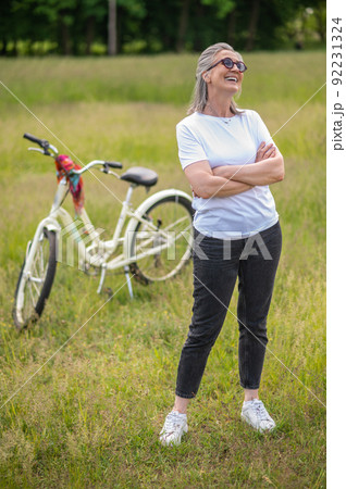 A cheerful woman in eyeglasses with a bike in the park 92231324