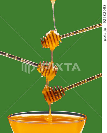 Fresh floral honey drips from a spoon into a spoon on a colored background. Organic vitamin food. 92232098