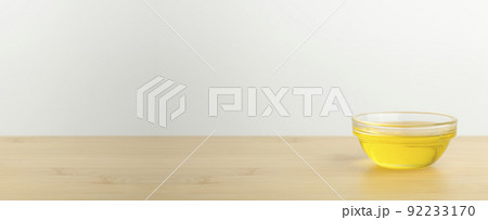 Oil in a glass bowl on a clean white banner background. Cosmetic or food oil background Oil in a glass bowl on a clean white banner background. Cosmetic or food oil background 92233170