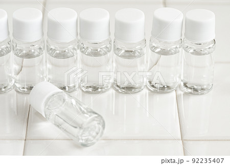 白いタイルの上に並べたプラスチック容器の化粧品サンプル 92235407
