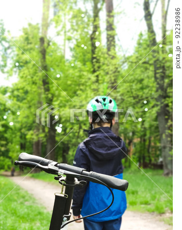 child alone in the park on a scooter in a helmet child alone in the park on a scooter in a helmet 92238986