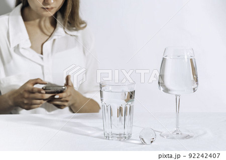 Casual style young woman texting on a smartphone. water glasses. Female model Casual style young woman texting on a smartphone. water glasses. Female model 92242407