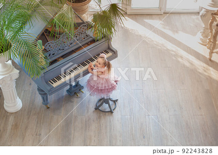 Overhead view of young girl playing grand piano in sunlight room 92243828