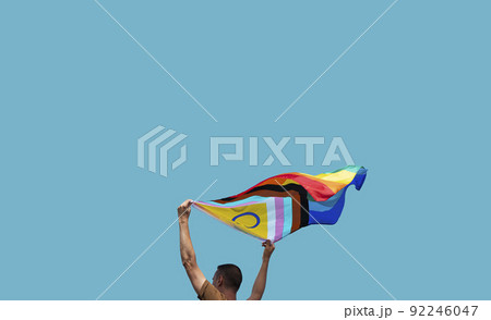man is waving a progress pride flag outdoors man is waving a progress pride flag outdoors 92246047