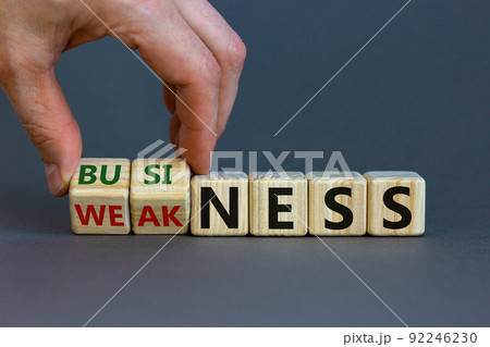 Business or weakness symbol. Businessman hand turns wooden cubes and changes the word 'weakness' to 'business'. Beautiful grey background, copy space. Business or weakness concept. Business or weakness symbol. Businessman hand turns wooden cubes and changes the word 'weakness' to 'business'. Beautiful grey background, copy space. Business or weakness concept. 92246230