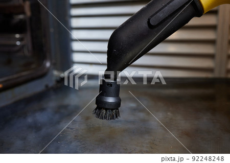 Experienced worker in rubber gloves steam-cleaning kitchen equipment. 92248248