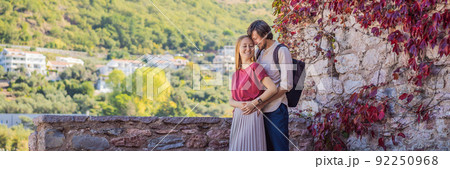 BANNER, LONG FORMAT Man and woman tourists on background of beautiful view of the island of St. Stephen, Sveti Stefan on the Budva Riviera, Budva, Montenegro. Travel to Montenegro concept 92250968