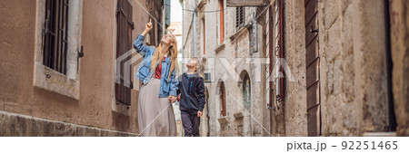 BANNER, LONG FORMAT Mom and son travelers enjoying Colorful street in Old town of Kotor on a sunny day, Montenegro. Travel to Montenegro concept BANNER, LONG FORMAT Mom and son travelers enjoying Colorful street in Old town of Kotor on a sunny day, Montenegro. Travel to Montenegro concept 92251465