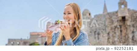 BANNER, LONG FORMAT Young woman tourist eating traditional pizza in the old town of Budva. Travel to Montenegro concept 92252181