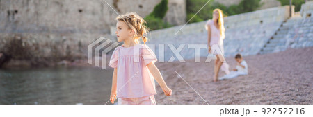 BANNER, LONG FORMAT Mother and two children daughter and son tourists on background of beautiful view St. Stephen island, Sveti Stefan on the Budva Riviera, Budva, Montenegro. Travel to Montenegro 92252216