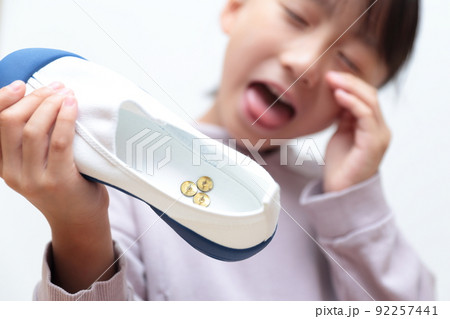上履きに画鋲が入っていてショックを受ける小学生の女の子 92257441